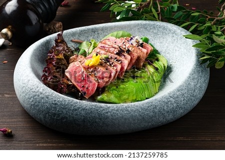Ahi tuna. Delicious Tuna Sashimi, raw sliced fish on black background. Traditional Japanese cuisine sashimi with tuna and avocado. maguro tataki ponzu Royalty-Free Stock Photo #2137259785