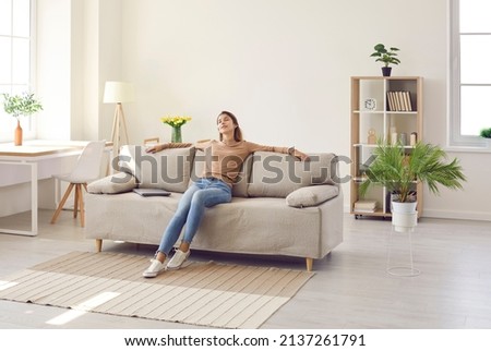 Clam millennial Caucasian girl sit rest on sofa in living room sleep or take nap. Happy young woman relax on comfortable couch furniture at home, daydream doze, relieve negative emotion. Stress free. Royalty-Free Stock Photo #2137261791