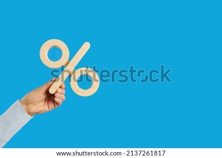 Percentage sign in human hand. Entrepreneur, client, customer holding percent symbol on blank solid blue text copyspace background. Business, finance, investment, tax increase, value added tax concept