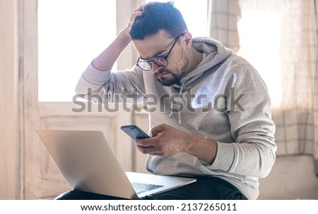 A man with glasses is working on a laptop.