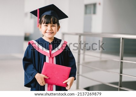 Portrait of a cute Asian graduated schoolgirl with graduation gown in school Royalty-Free Stock Photo #2137269879