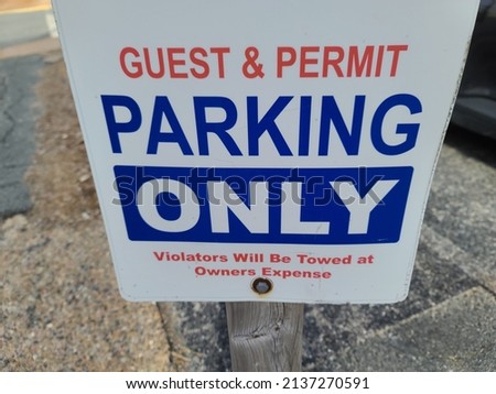 A sign that says "GUEST AND PERMIT PARKING ONLY VIOLATORS WILL BE TOWED AT OWNERS EXPENSE".