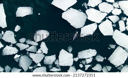 Kayak sailing between ice floes on the lake. Aerial drone view. Abstract nature background. Baikal lake, Siberia, Russia. Spring landscape Royalty-Free Stock Photo #2137272351