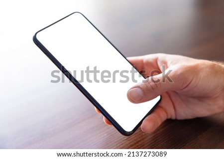 Close up photo of person holding mobile phone in hand, blank white screen mockup