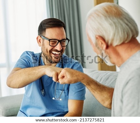 Doctor or nurse caregiver with senior man greeting with a fist at home or nursing home