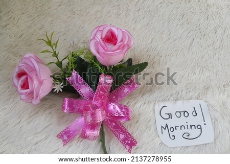 Good morning text and roses on soft fluffy fabric background. Selective focus.