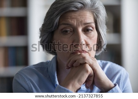 Close up worried middle-aged woman deep in sad thoughts, troubled with business or personal life concerns. Frustrated businesswoman thinks seated at workplace, feel distressed looks helpless concept Royalty-Free Stock Photo #2137327855