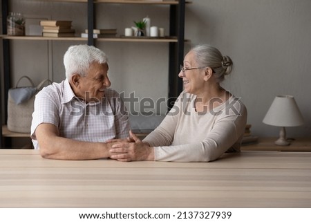 Happy marriage, eternal love, trustworthy harmonic relations between older spouses concept. Senior grandparents sit at table at home smile look at each other hold hands feel endearment, express caress Royalty-Free Stock Photo #2137327939