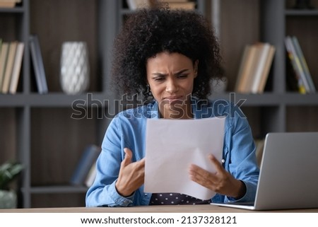 Annoyed frustrated African student girl receiving paper letter, rejection notice from university, feeling stress. Upset young Black employee woman reading document with bad dismissal news. Royalty-Free Stock Photo #2137328121