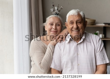 Portrait of grey-haired grandparents smile staring at camera feel satisfied, standing in living room, spend carefree retired life together. Happy marriage, pure love, good harmonic relations concept Royalty-Free Stock Photo #2137328199
