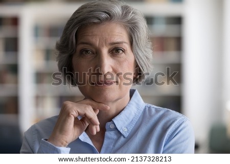 Close up head shot beautiful grey-haired woman touch chin with hand staring at camera, looks confident and serious, having elegant style, attractive appearance. Mature businesswoman portrait concept Royalty-Free Stock Photo #2137328213