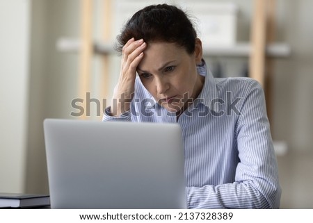 Shocked puzzled mature business lady reading bad news on Internet, touching head, feeling stress, headache, thinking over problems hard, looking at laptop screen, making difficult decision Royalty-Free Stock Photo #2137328389