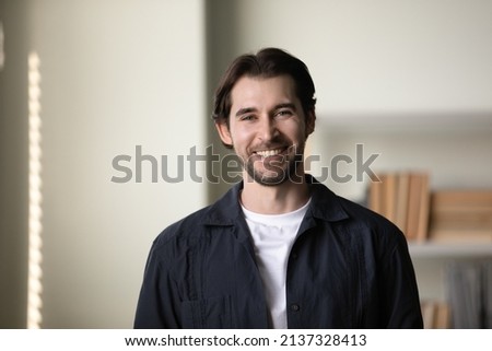 Positive successful millennial business professional man head shot portrait. Happy handsome confident young startup leader, company founder, posing in office, looking at camera with toothy smile