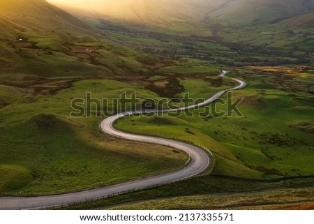 Long winding road in British rural countryside leading off into distance. Peak District, UK. Royalty-Free Stock Photo #2137335571