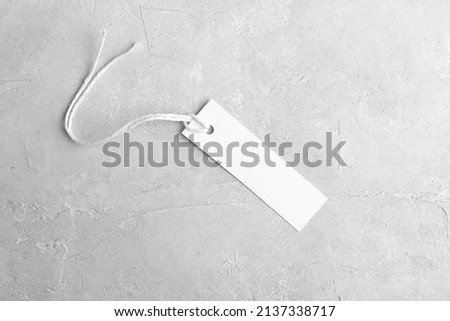 Rectangle strip white tag mockup with white cord, close up. Blank paper rectangular price tag mockup isolated on grey background with copy space, Sale and Black Friday concept