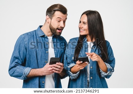 Shocked caucasian young couple girlfriend and boyfriend sharing news information photos online in social media networks, using mobile application on smart phone e-banking, isolated in white background