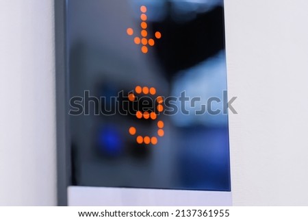 Digital elevator display showing orange floor number -3, third floor - lift going down at mall, hotel or business center - close up view. Technology and transportation concept