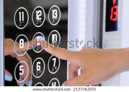 Woman finger pressing elevator button of ninth floor on lift control panel at mall, hotel or business center - close up view. Technology and transportation concept