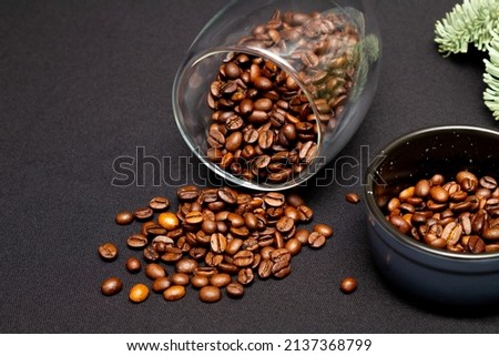 Composition of coffee beans spilling out of a cup on a dark gray background.