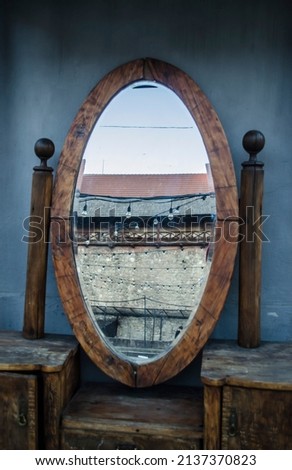 Vintage mirror in a wooden frame on a background of blue walls with a reflection of the city.Vertical photo of cityscape.