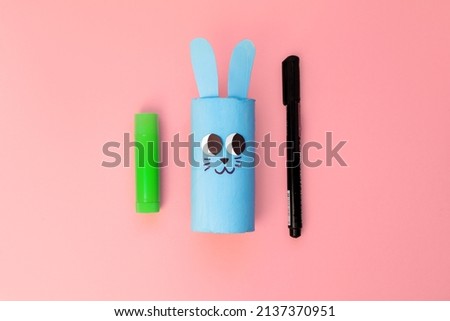 DIY crafts for kids, toilet tube roll, glue, paint on pink backround. Step by step bunny rabbit toy New Year, Easter christmas holidays decoration eco-friendly, recycle, reuse, handmade concept