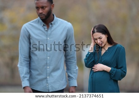 Front view portrait of a breakup with a husband leaving his sad pregnant wife in a park Royalty-Free Stock Photo #2137374651
