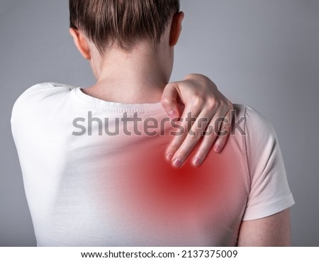 Woman suffering from shoulder blade pain. Trigger point. Hand holding shoulder with red spot closeup. Back injury. Health care, medicine concept. High quality photo Royalty-Free Stock Photo #2137375009