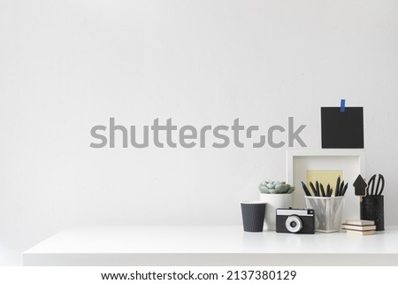 Home office desk, with empty table and desk supplies against white wall space