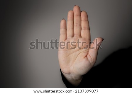 The woman's hand is raised forward with an open palm. Stop gesture, forbidding, rejecting, denying as a concept of equal rights for women, non-admission of violence, setting personal boundaries. Royalty-Free Stock Photo #2137399077