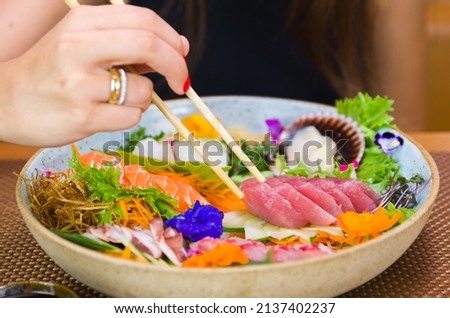 Woman eating delicious sushi, closeup on chopsticks