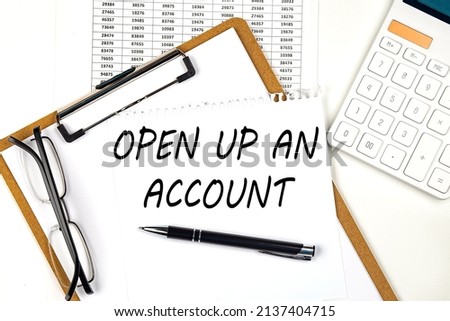 Text OPEN UP AN ACCOUNT on white paper on clipboard with chart and calculator