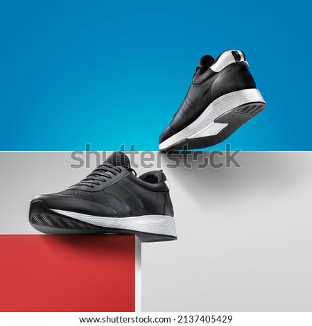 Shoes for the sport. Flying men's black running Shoe with fluttering laces isolated on a blue background. Product photography