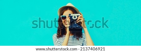 Summer portrait of happy smiling young woman photographer with vintage film camera on colorful blue background
