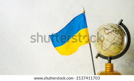 Globe and national flag of Ukraine. Ukraine in geopolitics, Russia's invasion of the territory of an independent state, war, killings of civilians.There are no people in the photo.