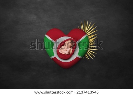 Newborn portrait on heart in color of national flag. Photography peace concept. Burundi