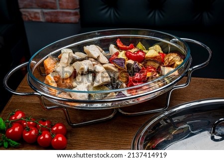 Stew with different types of fish and grilled vegetables. Halibut, salmon, paprika, zucchini, zucchini, tomato in a large portion in a restaurant