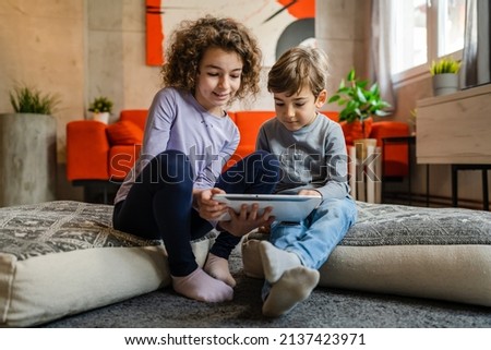 Siblings brother and sister boy and girl or children friends using digital tablet at home i room to watch video make a call or play online games leisure family concept real people copy space Royalty-Free Stock Photo #2137423971
