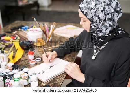 Young female in hijab creating clothes in workghop