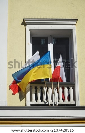 The national flags of Ukraine and Poland hangs in front of window as symbol of support Ukraine in Russian-Ukrainian war.
