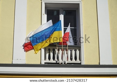 The national flags of Ukraine and Poland hangs in front of window as symbol of support Ukraine in Russian-Ukrainian war.
