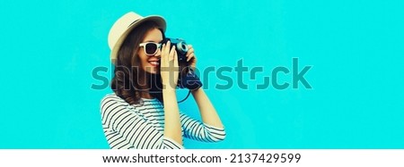 Summer portrait of happy smiling young woman photographer with vintage film camera on colorful blue background