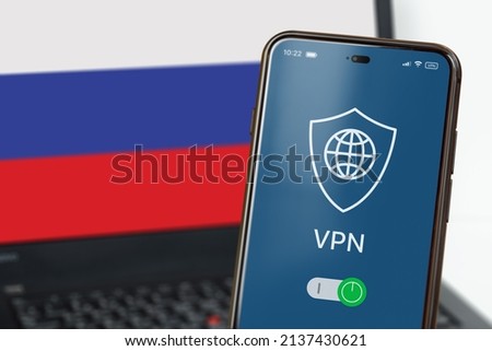 VPN in Russia. A smartphone with VPN turned on in the foreground and a laptop screen with the flag of Russia in the background. Using VPN on cell phone and computer. Selected focus Royalty-Free Stock Photo #2137430621