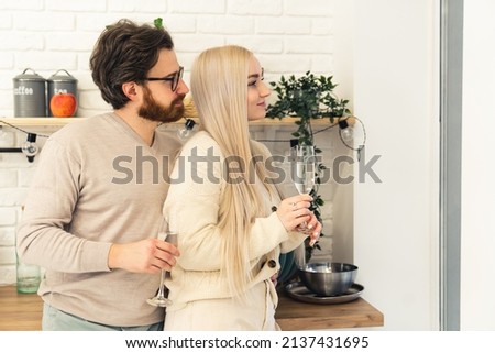 Married Caucasian couple staying and looking out the window holding glasses of water healthy lifestyle real estate medium shot copy space. High quality photo