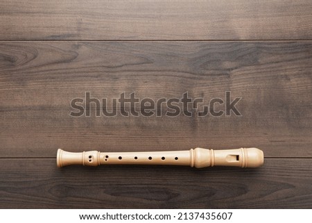 Overhead photo of block flute with copy space. Flat lay top-down composition of wooden recorder on the wooden background. Royalty-Free Stock Photo #2137435607