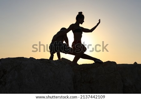 Silhouette of a woman and man dancing against a sea background