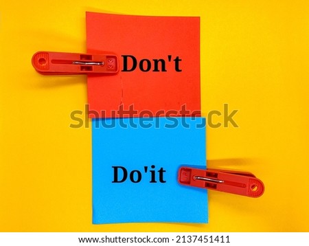 Red and blue paper with the concept words Don't and Do'it on a yellow background.
