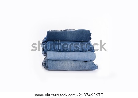 stack of blue jeans on a white background.

