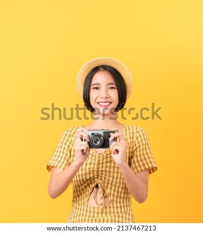 Young woman tourist holding camera and looking on white background.