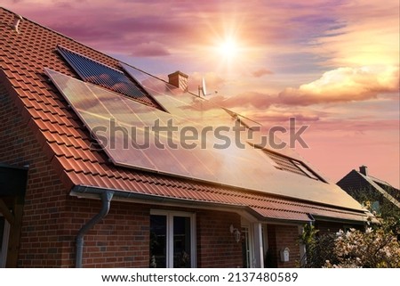 Photo collage of solar panels, photovoltaics on the red roof of a house and a beautiful sky with the setting sun. Alternative electricity source. Concept of sustainable resources Royalty-Free Stock Photo #2137480589