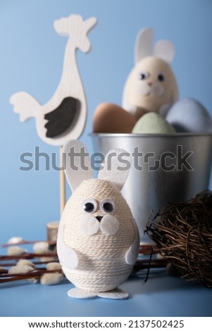 Easter composition of an egg in the form of a hare, a cart with eggs and a rooster figurine.